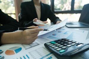 Two people are sitting at a table with a calculator and a stack of papers photo