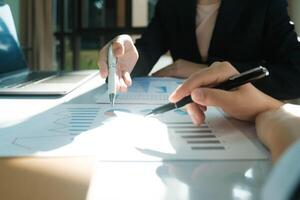 Two people are looking at a table with graphs and a pen photo