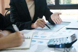 Two women in business suits are discussing a report on a table photo