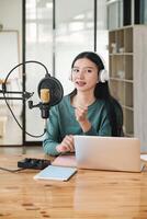 A woman is sitting at a desk with a microphone and a laptop photo