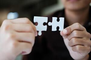 Two people holding a puzzle piece together. Concept of teamwork and collaboration. photo