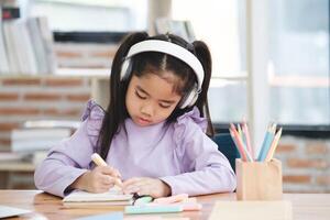 A young girl is sitting at a desk with a pencil and a notebook photo