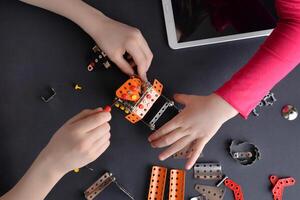 Children piece together robot from small metal parts and screws. Highlighting learning, teamwork, creativity, and interactive engagement photo