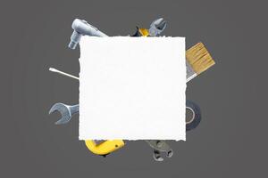 Clean paper surrounded by tools, brush, pliers, screwdriver, tape measure, adhesive tape, wrench. Ideal for text, logo promotion. Top view, flat lay composition. DIY concept photo