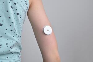 Child's hand with white sensor for continuous glucose monitoring. Concept of health, diabetes management, medical technology, and monitoring solutions photo