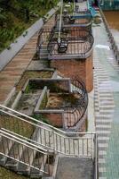 steps leading to the river with a footpath and iron guardrail, photo seen from above.