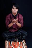 front view of a man praying on a prayer mat with a black background. photo