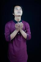 front view of a man raising his hands in prayer on a black background. photo