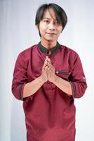 front view of a man wearing a koko shirt giving a salute on a white background. photo