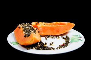 close up view of papaya fruit isolated on plate on black background. photo