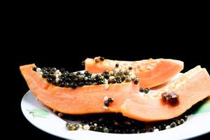 close up view of papaya fruit isolated on plate on black background. photo