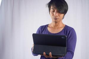 retrato de joven asiático hombre en pie y participación ordenador portátil computadora cuaderno en tecnología dispositivo aislado en blanco antecedentes. estilo de vida de negocio gente. foto