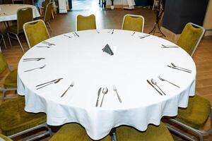 Serving in the restaurant is a white empty table, cutlery lies on the tablecloth, the interior of the catering establishment, preparation for the banquet, there are no people. fork on the table photo