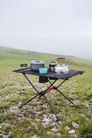 el concepto de un conjunto de utensilios para cámping en naturaleza, desayuno para dos en excursionismo condiciones, un marco mesa hecho de malla. foto