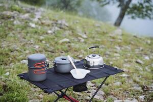 Breakfast of the tourist group at the halt in the mountains, cook food on a hike, metal utensils in the mountaineering, equipment for the kitchen in the campsite. photo