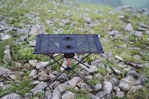 A picnic table stands on the rocks in nature, a frame folding table for food, a park in the mountains, photo