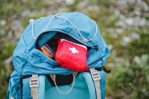 primero ayuda equipo para viaje es en el bolsillo de el mochila, emergencia asistencia en caso de lesión en el viaje un conjunto de medicamentos en un rojo bolsa, el concepto de un primeros auxilios equipo médico foto