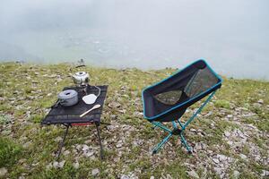 Picnic area high in the mountains, tourist furniture for camping in nature, compact folding chair, picnic set, fog in the forest. photo