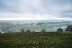 Cloudy morning in the Mountains of the Urals, green grass, river valley, expanses of Russia, steppe region, spring weather. photo