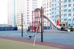 Children's play complex in the courtyard of a residential building, playground for children, swings, metal slide pipe, rubber asphalt coating. photo