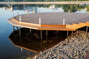 Round wooden pier on the river bank, a place for a boat mooring, a pedestal of boards, a platform for morning meditation, a city park in the morning there are no people photo