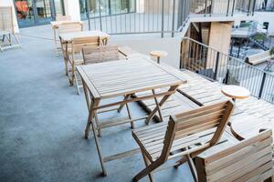 The interior of the outdoor cafe on the sidewalk, wooden tables, garden furniture, the design of the restaurant in the open air. photo