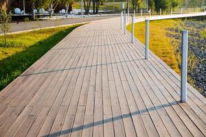 A pedestrian road made of boards, a wooden path, a place for walking in the park, a modern city recreation park, the lines go up. photo