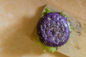 close up photo of a home-made purple burger placed on a ceramic table