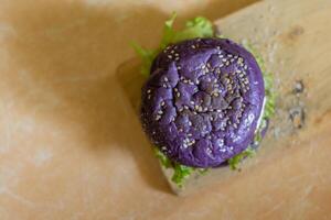 close up photo of a home-made purple burger placed on a ceramic table
