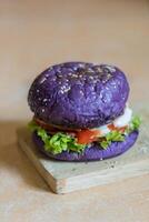 close up photo of a home-made purple burger placed on a ceramic table