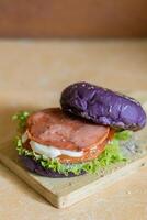 close up photo of a home-made purple burger placed on a ceramic table