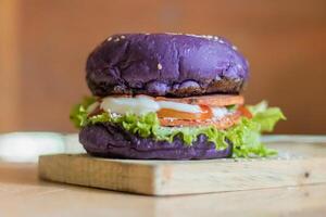 close up photo of a home-made purple burger placed on a ceramic table