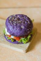 close up photo of a home-made purple burger placed on a ceramic table