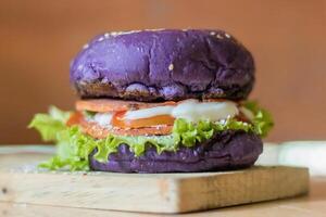 close up photo of a home-made purple burger placed on a ceramic table