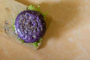 close up photo of a home-made purple burger placed on a ceramic table
