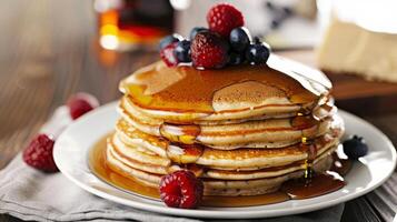delightful breakfast scene with stack of pancakes with syrup and fresh raspberries, blueberries, served on white plate. Tempting breakfast dessert option, culinary delights, brunch menus photo