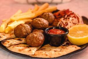 Meatballs Beef Portion served with potato, pita, salad, tomato, lemon and sauce in greek tavern. Mediterranean cuisine. Selective soft focus photo