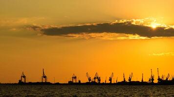 View of cranes in the Thessaloniki cargo port against a cloudy sky in the sunset. Greece photo