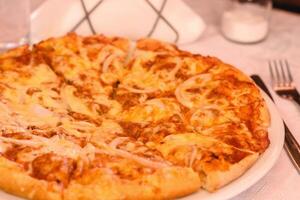 Large delicious BBQ pizza with gouda cheese, chicken, bacon, BBQ sauce in greek tavern. Table setting. Customer service. Mediterranean cuisine photo