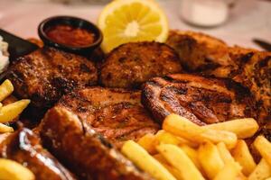 de cerca de mezcla parrilla incluye pollo pierna, panceta, embutido, tocino, hamburguesa, papas, rebanado Agave servido con limón y salsa en griego taberna. selectivo suave enfocar. Mediterráneo cocina foto