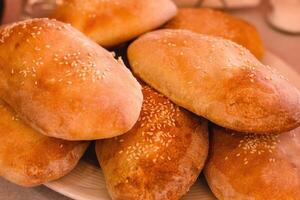 tradicional griego delicioso hecho a mano Pastelería pitsopsomo con sésamo en un blanco plato en griego taberna. hecho en casa un pan de cerca. Mediterráneo cocina. selectivo suave enfocar. foto