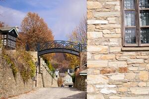 Black metal suspension bridge on an autumn street in Nymfaio Greece. Wrought iron grates, wooden frames in a stone house in the foreground photo