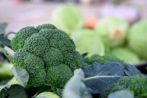 Green broccoli cabbage with leaves. Close-up view. Selective focus. Organic vegetables. Trading on the street from a tray. Healthy eating concept. Small farm business support. photo