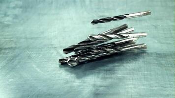 Drill bits fall on the table. On a gray background. Filmed is slow motion 1000 frames per second. High quality FullHD footage video