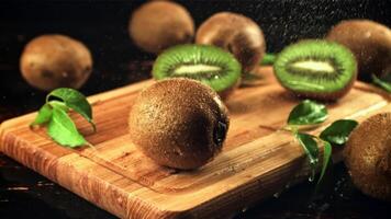 On the kiwi water droplets fall on the cutting board. On a black background. Filmed is slow motion 1000 frames per second. video