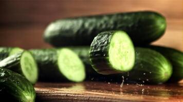 A piece of cucumber falls on the table and rotates. On a wooden background. Filmed is slow motion 1000 frames per second. video