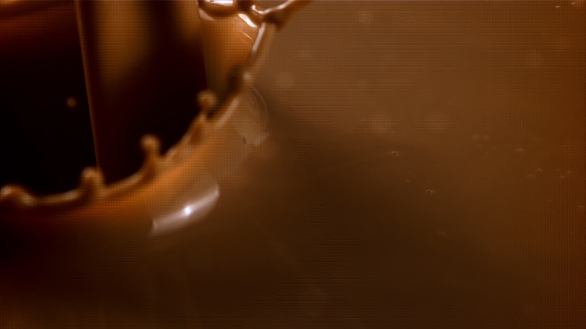 A stream of hot chocolate pours in with splashes. Macro background