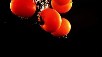 Tomatoes fall under the water with air bubbles. On a black background.Filmed is slow motion 1000 frames per second. High quality FullHD footage video