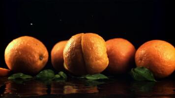 une Frais Orange chutes sur le table et se divise dans deux moitiés. sur une noir Contexte. filmé est lent mouvement 1000 ips. video