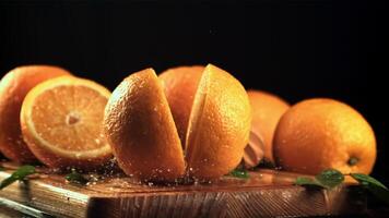 Two halves of an orange fall on a cutting board and split. On a black background. Filmed is slow motion 1000 fps. video